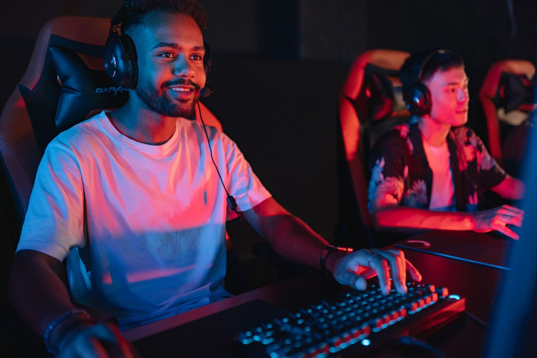 Dwóch graczy e-sportowych przy komputerach w kolorowym cybercafe